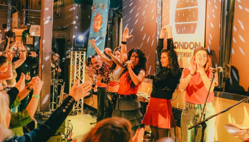 A band plays with their hands in the air for an energetic crowd at London Brewing Co-op in London, Ontario.