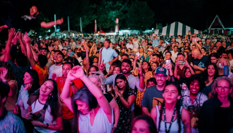 A large crowd of people gathered outdoors in Victoria Park located in London, Ontario enjoying live music from the Sunfest Festival