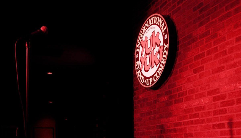 A Yuk Yuk's sign in front of a brick wall with a microphone in London, Ontario.