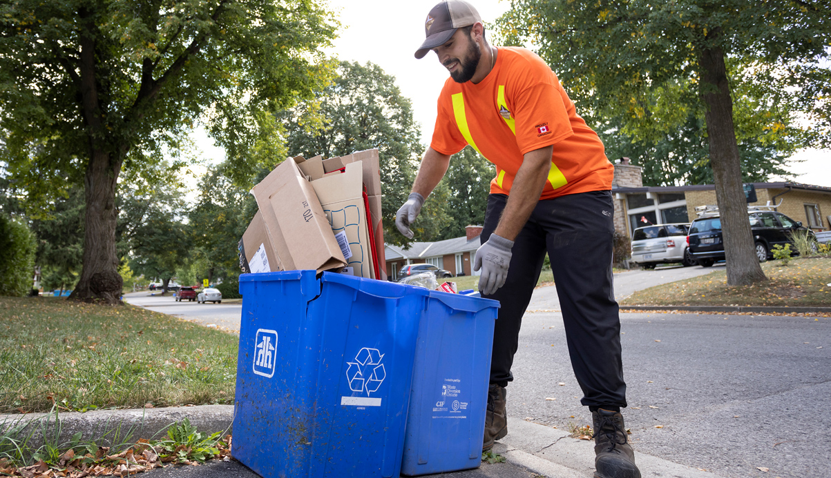 person attending to two blue recyle bins