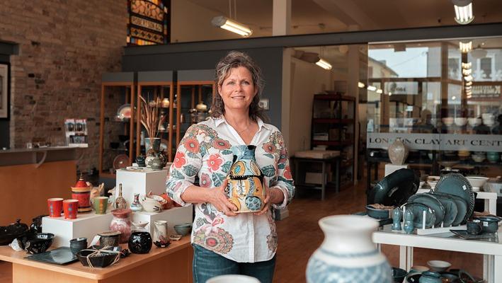 A woman holding ceramic pottery in the middle of the main showroom of the London Clay Art Centre located in London, Ontario