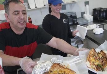 A man serving food from Abe's Subs & Wraps to customers located in London, Ontario