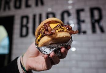 A hand holding up a burger from Burger Burger located in London, Ontario