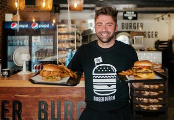 Owner Kirk Anastasiadis holding two trays of food from Burger Burger located in London, Ontario