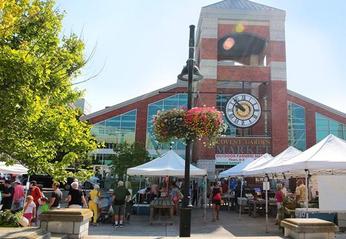 Exterior view of Covent Garden Market's main entrance with various vendors selling  fresh produce outdoors located in London, Ontario
