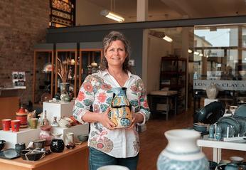 A woman holding ceramic pottery in the middle of the main showroom of the London Clay Art Centre located in London, Ontario