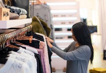 Owner of Needs/Wants Boutique Kathleen Meliton looking through clothing on display at her store