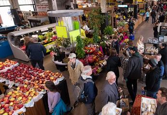 Groups of people walking and shopping with various vendors selling fresh produce at The Market at the Western Fair District