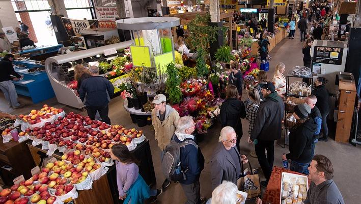 Groups of people walking and shopping with various vendors selling fresh produce at The Market at the Western Fair District