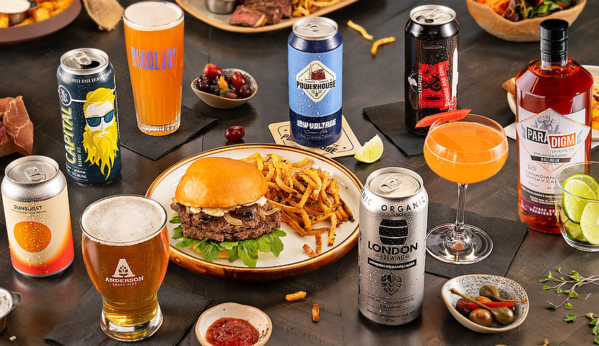 Table top view of various cans of beer and food with full glasses of beer from breweries and distilleries in London, Ontario