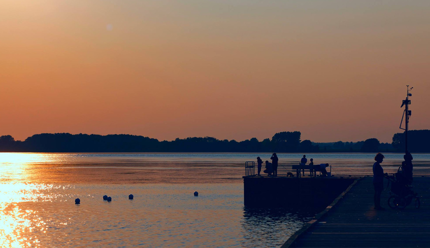 Silhouettes of people at a dock by a body of water looking at the sunset set in Chatham-Kent, Ontario