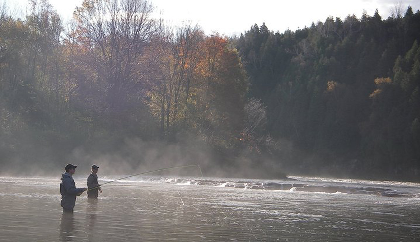 Two people fly fishing in a body of water on an early fall morning in Bayfield, Ontario 