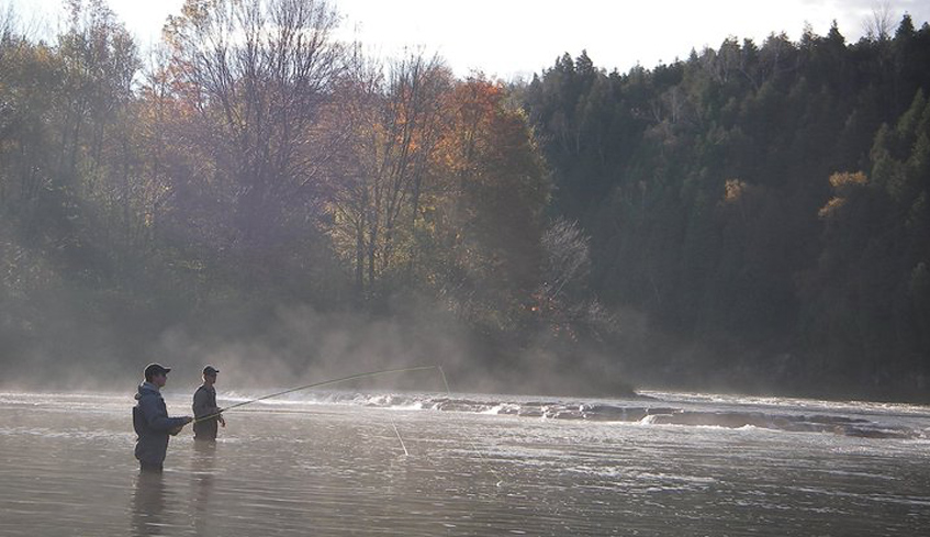 Two people fly fishing in a body of water on an early fall morning in Bayfield, Ontario